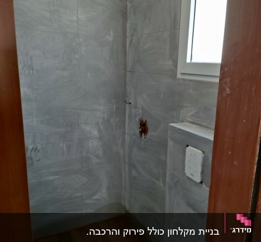 חדר אמבטיה בשיפוץ עם קירות אריחים אפורים